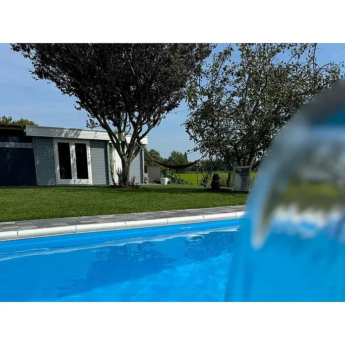 Fjordholz Gartenhaus Tobi 28 B - Außenmaß inkl. Dachüberstand (B x T): 550 x 400 cm, Holz, Naturbelassen - Ein leuchtend blauer Swimmingpool in einem Garten mit grauem Schuppen, grünem Rasen und Bäumen unter blauem Himmel.