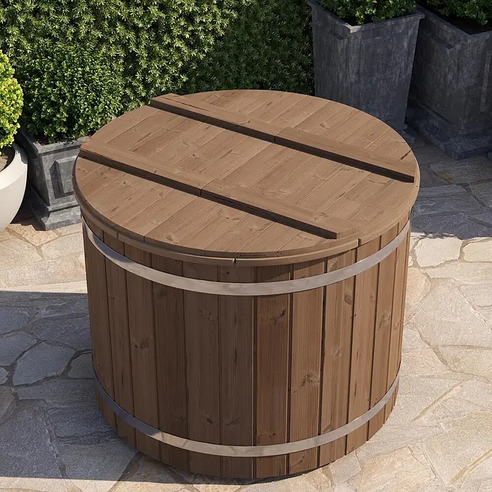 Tuindeco Eisbad - Ø x H: 133 x 109 cm, Natur - Dunkelbraune Holz-Außenwanne mit segmentiertem Deckel und Silberbändern, auf Steinterrasse von Grünpflanzen umgeben.