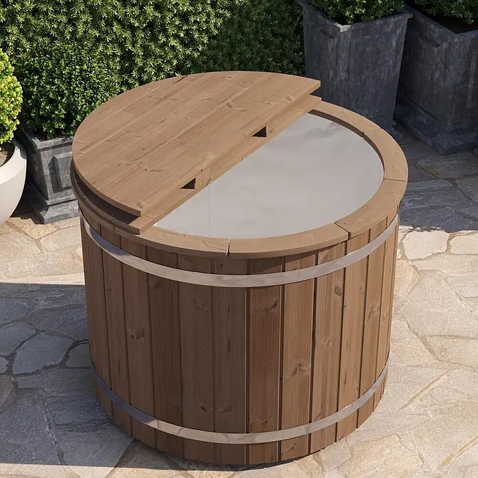 Tuindeco Eisbad - Ø x H: 133 x 109 cm, Natur - Hölzerner Badezuber mit teilweise geöffnetem Deckel, auf einer Steinterrasse inmitten von Grünpflanzen.