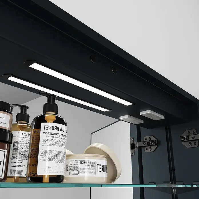 Disbain Armario con espejo LED Kenya - An x Al: 80 x 75 cm, Metal, Vidrio - Armario de baño azul oscuro con iluminación LED interior y estantes de cristal, que contiene productos para el cuidado de la piel. Una puerta está entreabierta.