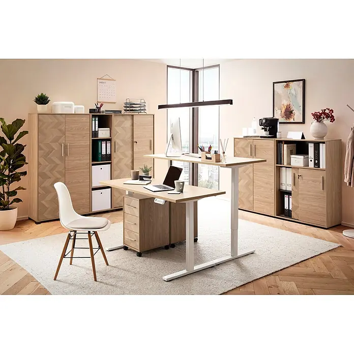 Schildmeyer Arezzo Rollcontainer - L x B x H: 39,1 x 32,6 x 59,7 cm, Eiche/Fischgräten, Anzahl Schubladen: 3 Stk. - Ein hellbrauner und weißer zweistufiger Stehschreibtisch mit Laptop und Monitor in einem modernen Büro mit passenden Schränken.