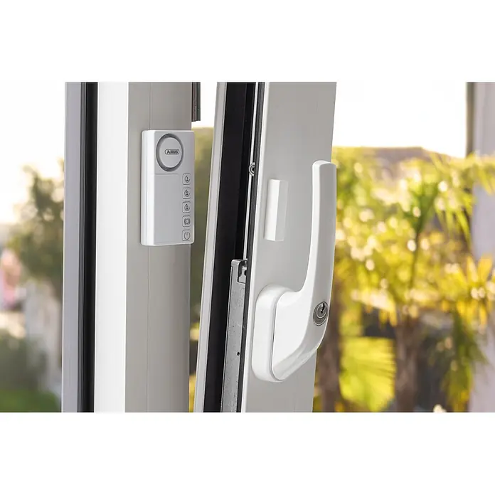 Abus Alarmanlage Time2Close Window Countdown Alarm - Weiß, 15 x 43 x 85 mm - Weißes ABUS Fenster-Sicherheitssystem mit Alarmeinheit, Magnetsensor und abschließbarem Griff, an einem geöffneten Fenster montiert.