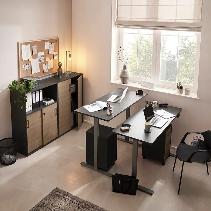 Schildmeyer Metz Rollcontainer - L x B x H: 39,1 x 32,6 x 59,7 cm, Anthrazit/Canello, Anzahl Schubladen: 3 Stk. - Zwei schwarze höhenverstellbare Schreibtische in einem Büro, ergänzt durch eine schwarze und holzfarbene Aufbewahrungseinheit und einen schwarzen Stuhl.