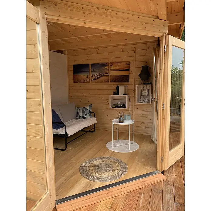 Fjordholz Gartenhaus Birger 44 - Außenmaß inkl. Dachüberstand (B x T): 448 x 298 cm, Holz, ohne Imprägnierung - Gemütliches Holzgartenhaus-Interieur mit Sofa, Kaffeemaschine und Dekoration.