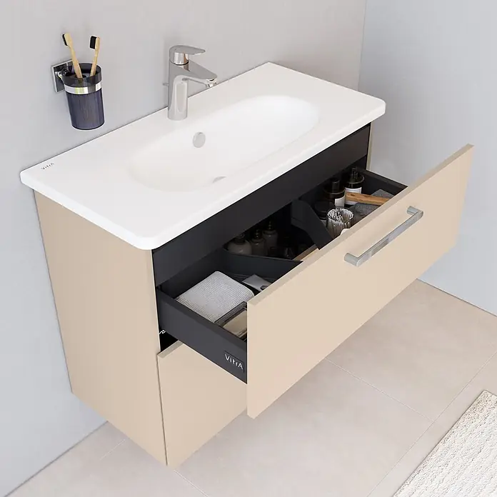 VitrA Badmöbel-Set Root Flat - B x T x H: 80 x 37 x 65 cm, Sahara Beige, Hochglänzend - Sandfarbener Badunterschrank mit weißem Waschbecken, Chromarmatur und geöffneter dunkelgrauer Schublade mit Toilettenartikeln.