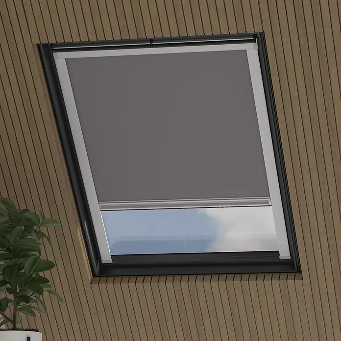 Dachfensterrollo Sky 2.0 - S06, Grau, Manuell - Dunkelgraues Verdunkelungsrollo, das ein Dachfenster in einer Holzvertäfelung teilweise abdeckt.