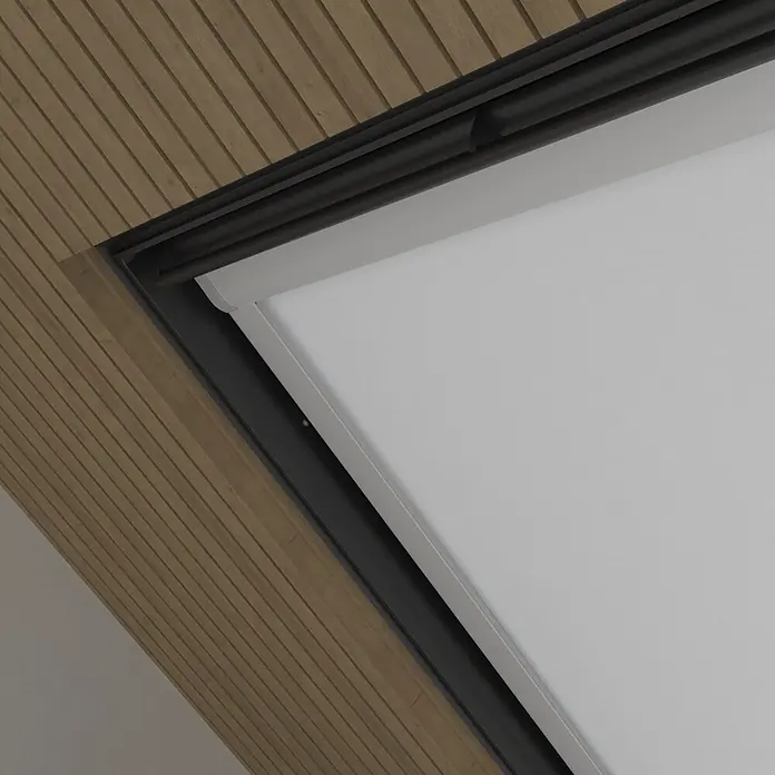 Dachfensterrollo Sky 2.0 - C02, Weiß, Manuell - Weißes Rollo in einem schwarz gerahmten Dachfenster, eingefasst in eine braune Holzlamellendecke.