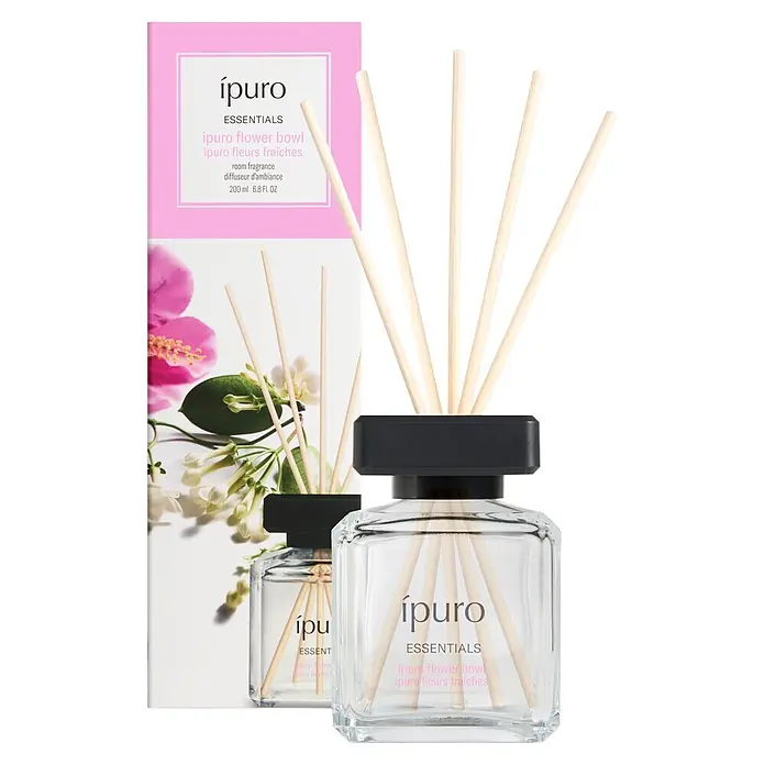Ipuro Essentials Raumduft - Flower Bowl, 200 ml - Ein ipuro Raumduft-Diffusor-Set mit Klarglasflasche, schwarzer Kappe und Holzstäbchen, zusammen mit seiner pink-weißen Produktverpackung.