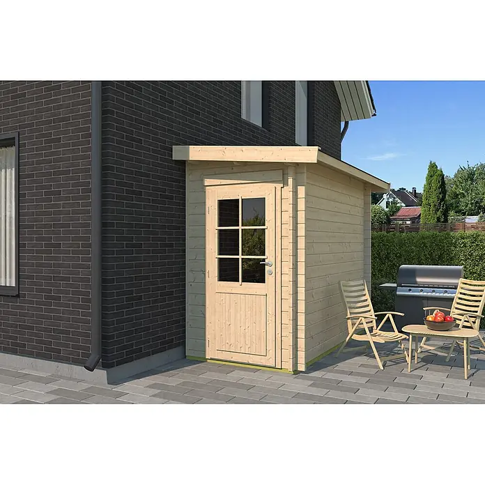 Fjordholz Gartenhaus Pulti 44 B - Außenmaß inkl. Dachüberstand (B x T): 150 x 300 cm, Holz, Naturbelassen - Kleiner Geräteschuppen aus hellem Holz mit Tür und Fenster, auf einer gepflasterten Terrasse neben einem dunklen Backsteinhaus.