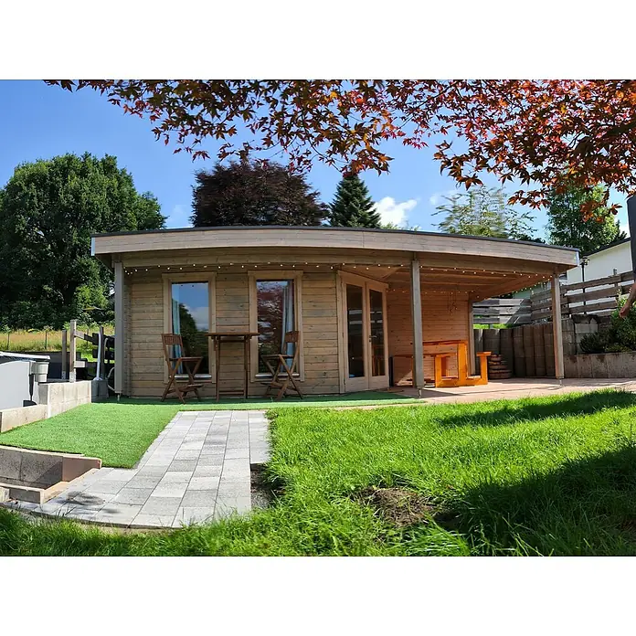 Fjordholz Gartenhaus Nora 44 I Modern - Außenmaß inkl. Dachüberstand (B x T): 725 x 320 cm, Holz, ohne Imprägnierung - Gartenhaus aus Holz mit geschwungenem Dach und überdachter Terrasse, in einem grünen Garten mit gepflastertem Weg.