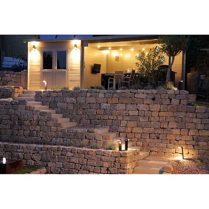 Fjordholz Gartenhaus Gent 28 B - Außenmaß inkl. Dachüberstand (B x T): 691 x 298 cm, Holz, ohne Imprägnierung - Außenwegleuchten und Lichterketten beleuchten einen gemütlichen Gartenschuppen mit Steintreppen bei Nacht.