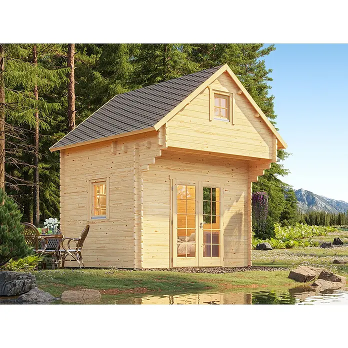 Fjordholz Gartenhaus Ontario 44 - Außenmaß inkl. Dachüberstand (B x T): 354,4 x 388,8 cm, Holz, ohne Imprägnierung - Ein helles Holz-Blockhaus mit dunklem Schindeldach, an einem See in malerischer Naturkulisse mit Bäumen und Bergen, mit einer Außensitzgruppe.