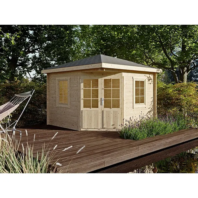 Fjordholz Gartenhaus Evelyn 3A - Außenmaß inkl. Dachüberstand (B x T): 320 x 320 cm, Holz, Naturbelassen - Heller Holz-Gartenschuppen mit dunklem Dach auf einer Terrasse, umgeben von Grün und lila Blumen, am Wasser.
