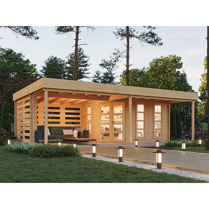 Fjordholz Gartenhaus Susan 44 - Außenmaß inkl. Dachüberstand (B x T): 785 x 505 cm, Holz, Kiefer/Pinie Imprägnierung - Gartenhaus aus hellem Holz mit überdachter Terrasse in einem üppigen Garten, beleuchtet in der Dämmerung, mit Sitzbereich und Wegeleuchten.