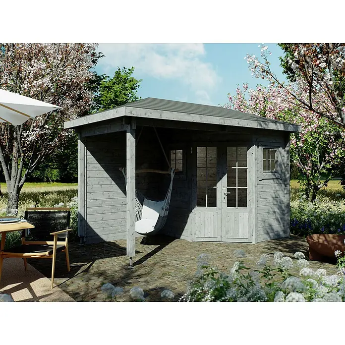 Fjordholz Gartenhaus Evelyn 1B - Außenmaß inkl. Dachüberstand (B x T): 380 x 200 cm, Holz, Naturbelassen - Grau lasiertes Gartenhaus aus Holz mit Veranda und Hängesessel auf einer Steinterrasse im blühenden Garten.