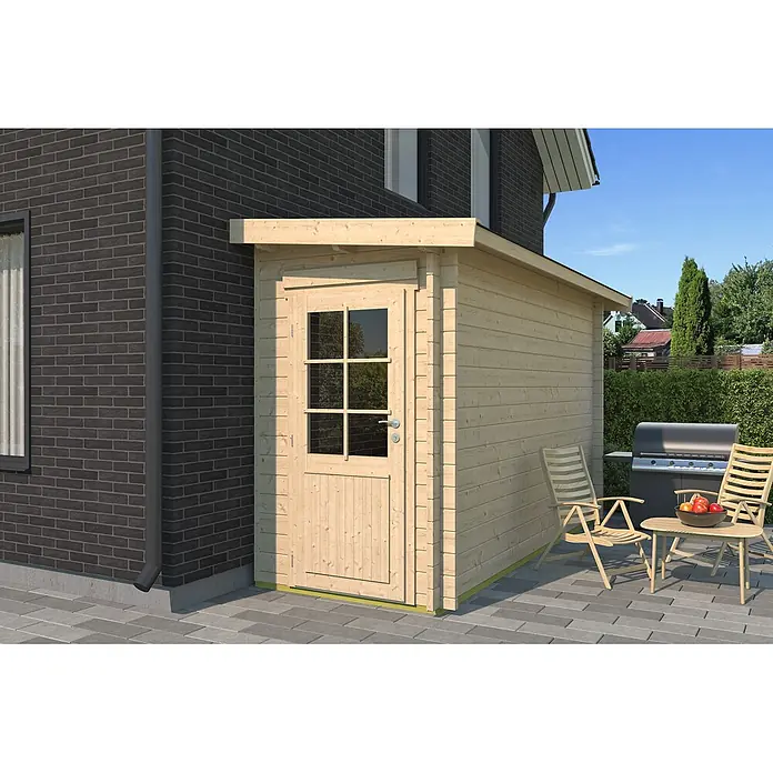 Fjordholz Gartenhaus Pulti 44 C - Außenmaß inkl. Dachüberstand (B x T): 150 x 400 cm, Holz, Naturbelassen - Helles Holz-Gartenhaus mit Fenstertür auf einer gepflasterten Terrasse neben einem Haus, ideal zur Aufbewahrung.