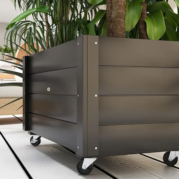 Outsunny Hochbeet - 89 x 48 x 47 cm, Holz, Schwarz - Dunkelgrauer, lattenförmiger Pflanzkasten auf Rollen, gefüllt mit großen Grünpflanzen, auf Holzboden.