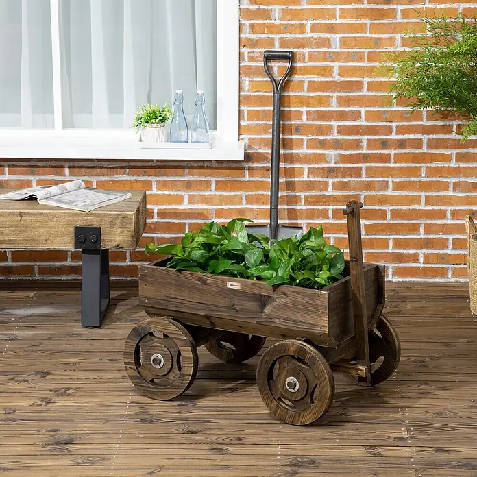 Outsunny Hochbeet - Holz, Verkohlt - Pflanzwagen aus dunklem Holz mit Grünpflanzen, auf einer Holzterrasse vor Ziegelwand.