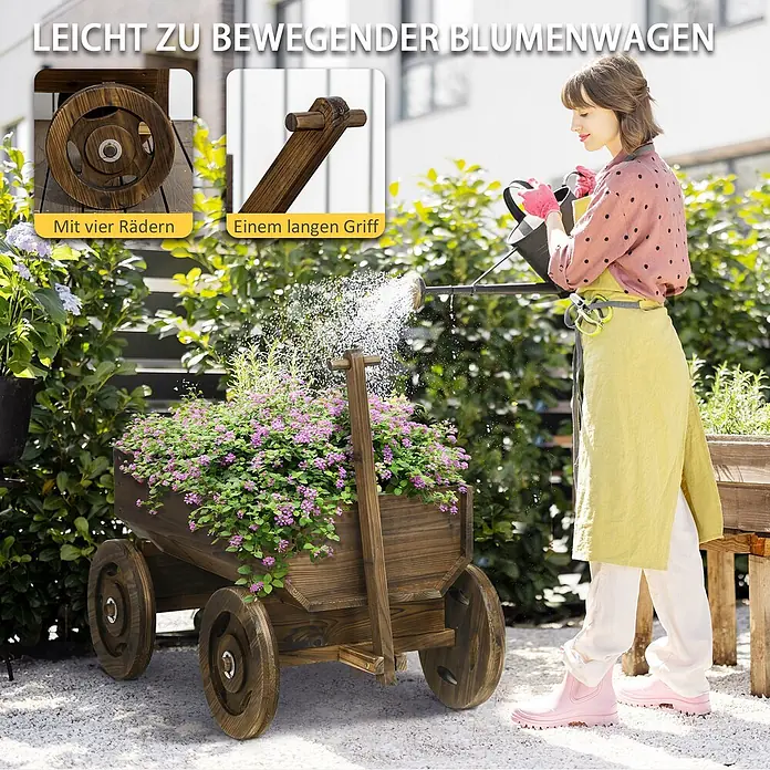 Outsunny Hochbeet - Holz, Verkohlt - Dunkler Blumenwagen aus Holz mit vier Rädern und langem Griff, bepflanzt mit rosa Blumen, wird im Garten gegossen.