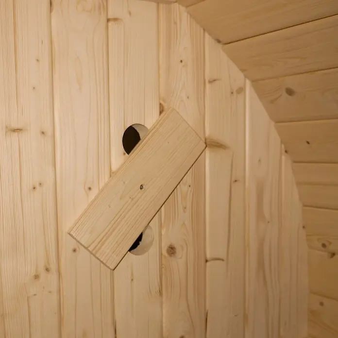 Home Deluxe Fasssauna CUBE L - Elektroofen, Holz - Verstellbare Holz-Lüftungsklappe aus hellem Naturholz, auf Holzwand montiert und Öffnung teilweise abdeckend.