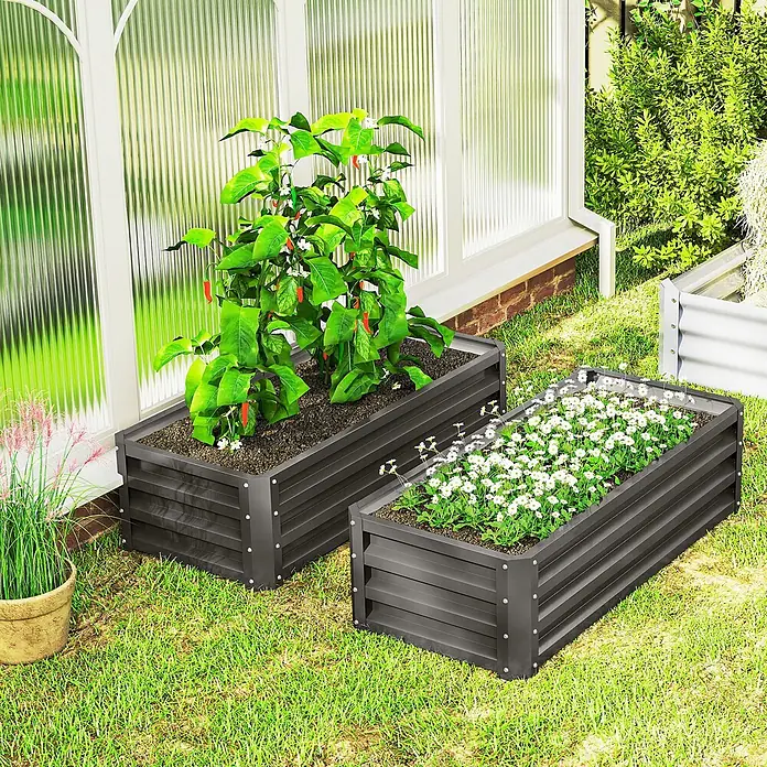 Outsunny Hochbeet - 110 x 50 x 30 cm, Stahl, Dunkelgrau - Zwei dunkelgraue Hochbeete aus Wellmetall auf Rasen. Eines mit Paprikapflanze, das andere mit weißen Blumen, neben einem Gewächshaus.