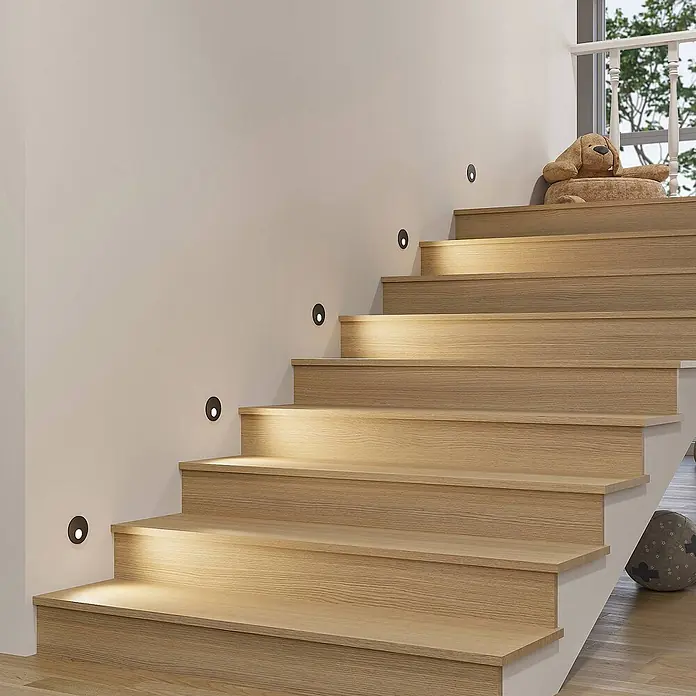 Arcchio Wandleuchte Vexi - L x B x H: 7,5 x 7,5 x 4,5 cm, schwarz - Dunkle, ovale Stufenleuchten spenden warmes Licht entlang einer Holztreppe.