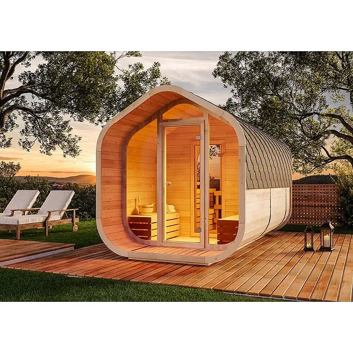 FinnTherm Fasssauna ScandiCube Wave Deluxe - Holz, L x B x H: 406 x 237 x 249 cm - Moderne ovale Außensaunakabine aus hellem Holz mit dunklem Dach, im Garten mit Holzterrasse und Liegestühlen für ein Wellness-Erlebnis.