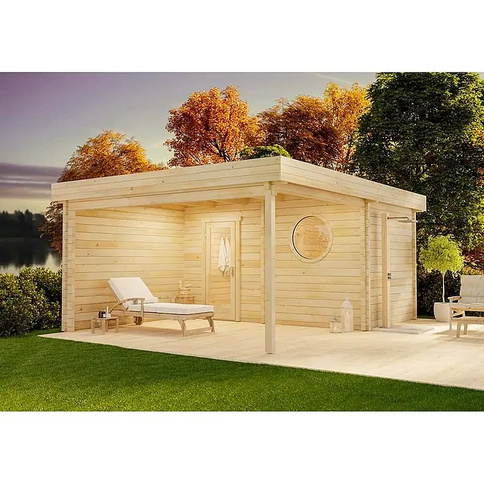 FinnTherm Saunahaus Cubus 70 Royal - L x B x H: 441 x 544 x 236 cm - Helle Holz-Gartensauna mit überdachter Veranda, Liege und Außendusche am See mit Herbstbäumen.