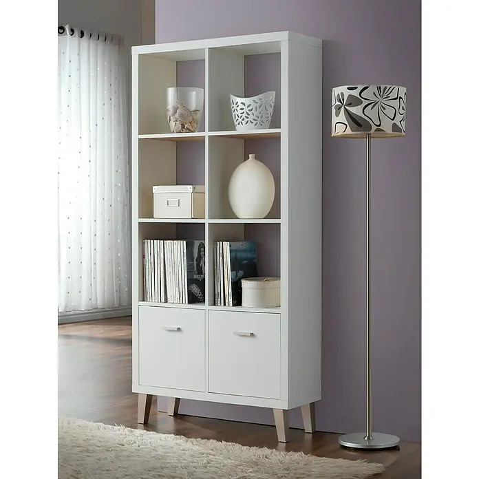 Estantería de madera Venecia - L x An x Al: 29 x 80 x 168 cm, MDF, Blanco - Estantería blanca con seis compartimentos y dos cajones, decorada con estilo, junto a una lámpara de pie en un espacio moderno.