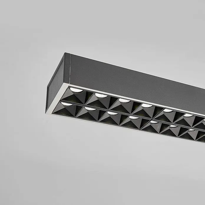 Arcchio Pendelleuchte Jolinda - alu / grau / zink, silber (RAL 9006) - Dunkelgraue lineare LED-Leuchte mit silbernem Rand und pyramidenförmigen Reflektoren, die helles Licht abgibt.