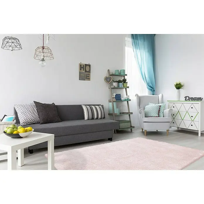 Kayoom Hochflorteppich Bali - Puderrosa, 230 x 160 cm, 100 % Polyester - Einladendes Wohnzimmer mit grauem Sofa, rosa Teppich und weißer Kommode. Dekorative Elemente vervollständigen das harmonische Ambiente.