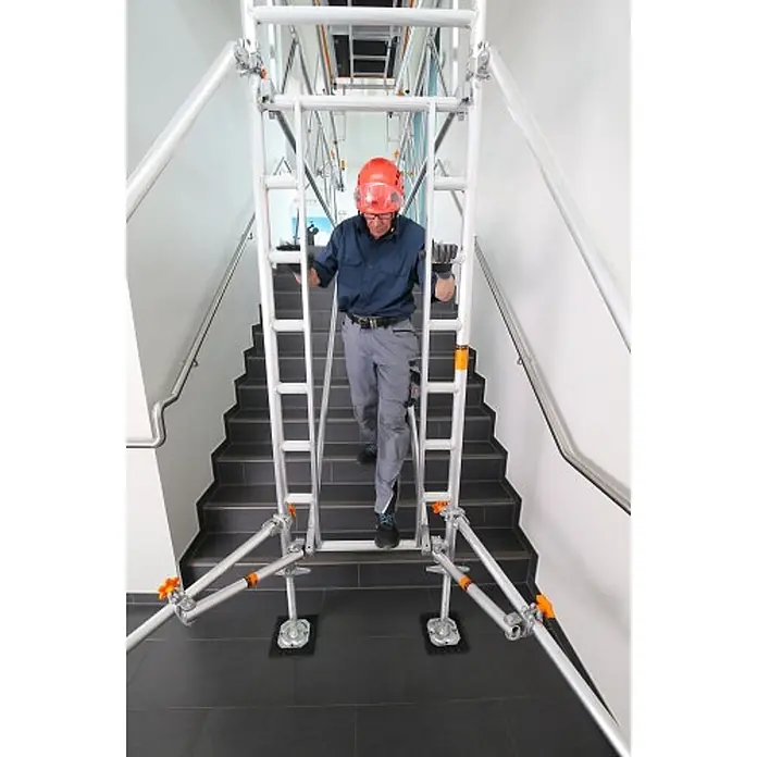Layher Rollgerüst Treppen-Kit für Fahrgerüst Uni Standard P2 mit 2 Durchgängen 7,73m AH - Arbeitshöhe: 7.730 m - Verstellbares Aluminium-Rollgerüst für Treppen mit einem Arbeiter, der darin hochsteigt.