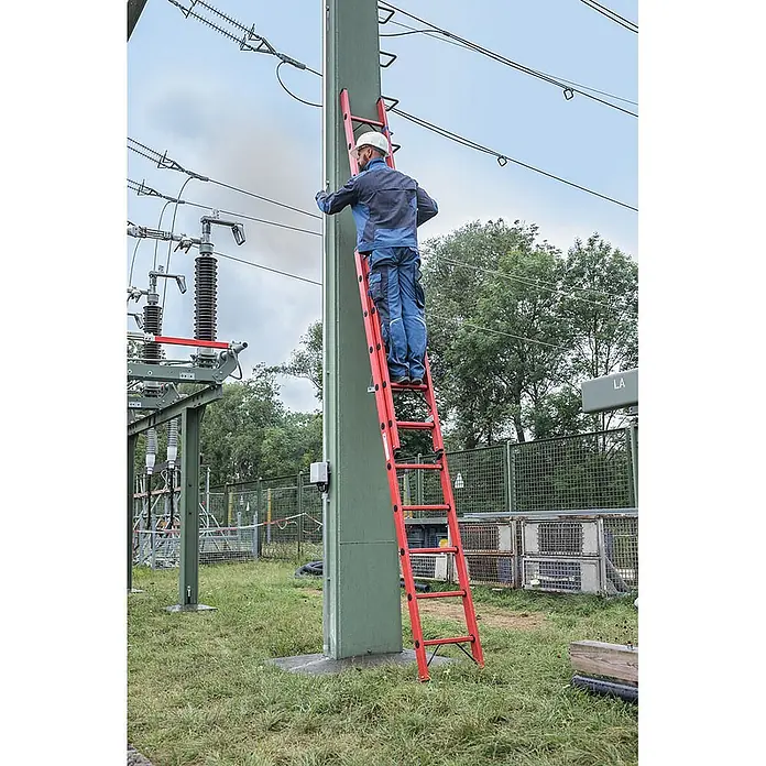 Munk Schiebeleiter Vollkunststoff Sprossen-Schiebeleiter 2x8 Sprossen - Anzahl Tritte: 8 Stk., Arbeitshöhe: 5.200 m, Kunststoff - Rote, nichtleitende Leiter, die von einem Arbeiter in einem Umspannwerk an einer großen grünen Säule zur Wartung verwendet wird.