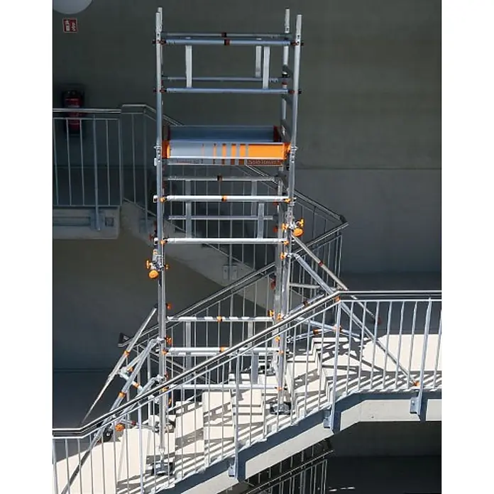 Layher Rollgerüst Treppen-Kit für Fahrgerüst SoloTower mit 2 Durchgängen 4,65m AH - Arbeitshöhe: 4.650 m - Aluminium-Rollgerüst mit orangen Akzenten, auf einer mehrstufigen Betontreppe für sicheren Zugang aufgebaut.