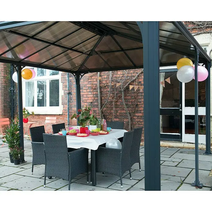 Palram – Canopia Pavillon Martinique 5000B x T: 493 x 359,3 cm, Farbe Gestell: Anthrazit, Aluminium - Einladende Szene mit einem eleganten Pavillon, einem Tisch und Stühlen, perfekt für eine stilvolle Gartenparty im Freien.