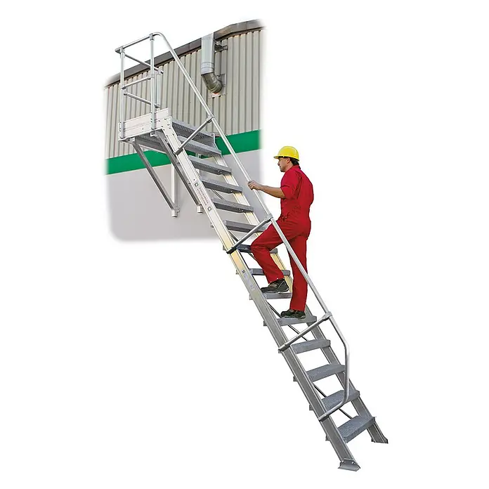 Munk Raumspartreppe Treppe mit Plattform 60° inkl. einen Handlauf, 1000mm Stufenbreite, 10 Stu - Breite: 108,5 cm - Silberne Industrietreppe mit Geländer, an einem Gebäude befestigt, von einem Arbeiter in Rot bestiegen.