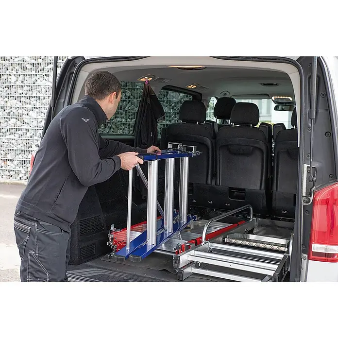 Munk Podestleiter Einsteckteil Plus 3 Stufen für steckbare Plattformleiter - Aluminium - Mann lädt ein modulares blaues, rotes und silbernes Leitersystem in einen Lieferwagen. Für einfachen Transport konzipiert.