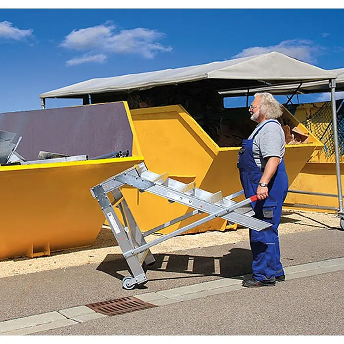 Munk Arbeitsplattform Arbeitspodest fahrbar Aluminium geriffelt 800mm Stufenbreite 5 Stufen - Anzahl Tritte: 5 Stk., Arbeitshöhe: 3.000 m, Aluminium - Mann nutzt eine tragbare, silberne Laderutsche mit Rollen, um Material in einen großen gelben Abfallcontainer zu leeren.
