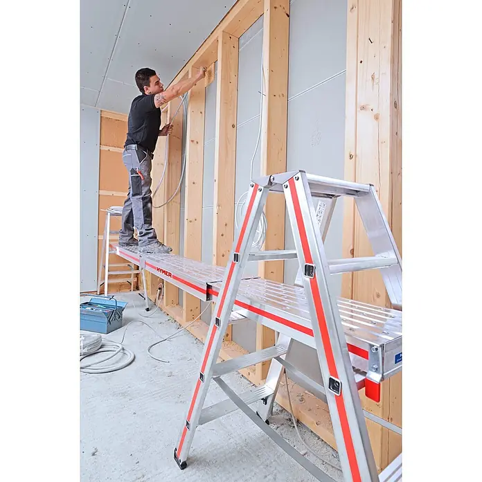 Hymer Arbeitsplattform Alu Diele Teleskopdiele Telesteg 1,24-4m Länge - Aluminium - HYMER Aluminium-Arbeitsplattform mit roten Akzenten, die einen Arbeiter bei der Kabelinstallation an einer Holzwand stützt.