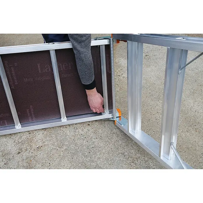 Layher Arbeitsplattform Arbeitsplattform TOPIC 1065 klappbar - Anzahl Tritte: 3 Stk., Arbeitshöhe: 2.650 m, Aluminium - Eine Hand montiert ein silbernes Aluminium-Modulgerüst, befestigt einen Abschnitt mit brauner rutschfester Arbeitsfläche.