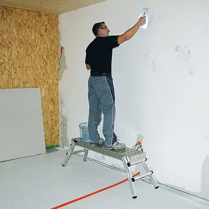 Munk Arbeitsplattform Aluminium Arbeitsplattform mit Klappfüßen - Anzahl Tritte: 2 Stk., Arbeitshöhe: 2.500 m, Aluminium - Robuste Aluminium-Arbeitsplattform, die einen Mann beim Verputzen einer Wand unterstützt.