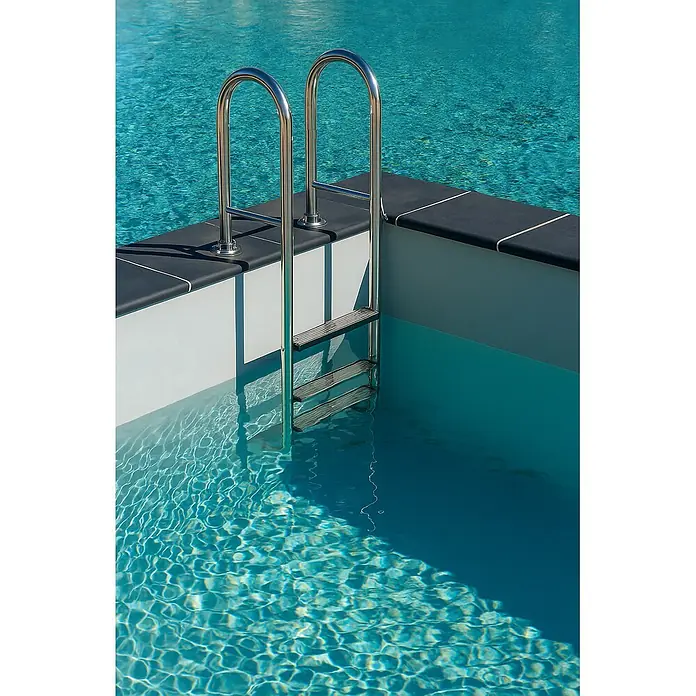 Ideal Eichenwald Anlegeleiter Poolleiter Modell 02 Tina klappbar Beckentiefe 1060mm 3 Stufen - Anzahl Tritte: 3 Stk., Belastbarkeit: 120 kg, Edelstahl - Edelstahl-Schwimmbadleiter mit drei Stufen, teilweise im klaren blauen Wasser, befestigt am dunkelgrauen Beckenrand.
