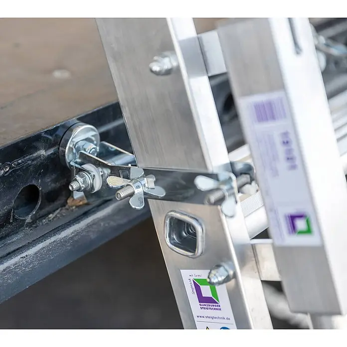 Munk Anlegeleiter Stufen-Anlegeleiter LKW inkl. Magnet Montagesatz mit 5 Stufen und Ausstiegs - Anzahl Tritte: 5 Stk., Arbeitshöhe: 3.150 m, Aluminium - Silberne Aluminiumleiter mit einer robusten Metallklemme und Flügelmuttern an einer dunklen Oberfläche befestigt.