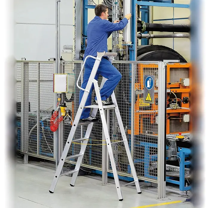 Zarges Stehleiter gebördelte Stehleiter Meistertritt S mit großer Plattform und Ablage 3 St - Anzahl Tritte: 3 Stk., Arbeitshöhe: 2.800 m, Aluminium - Arbeiter auf einer Aluminium-Sicherheits-Stehleiter mit großer Plattform bei Wartungsarbeiten an Industriemaschinen.