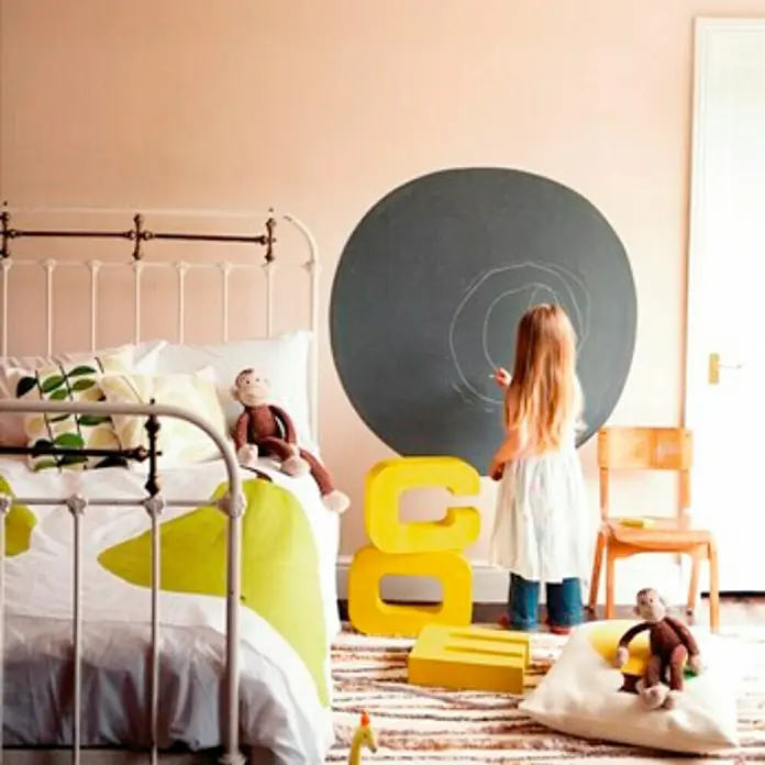 Bruguer Esmalte de pizarra Acrylic - Negro, 750 l, Mate - Una habitación infantil con pizarra, cama y juguetes. La pizarra en la pared es un elemento de diseño interactivo para niños.