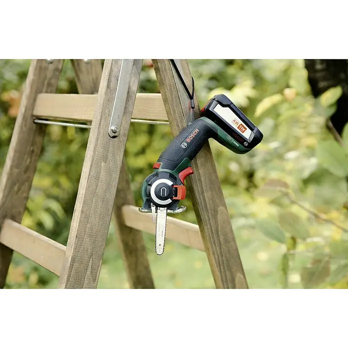 Bosch Power for All 18V Sierra NanoBlade AdvancedCut 18 - Número de revoluciones de marcha en vacío: 7.000 r.p.m., 18 V, 1 batería - La imagen muestra una sierra de podar inalámbrica de Bosch apoyada en una escalera de madera. La sierra tiene una batería y una correa de mano.