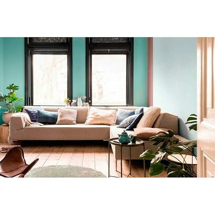 Bruguer Esmalte de color Acrylic Multisuperficie - Marfil Claro, Satinado, 750 ml, Base de agua - Sofá beige con almohadas en una sala de estar con pisos de madera y plantas.