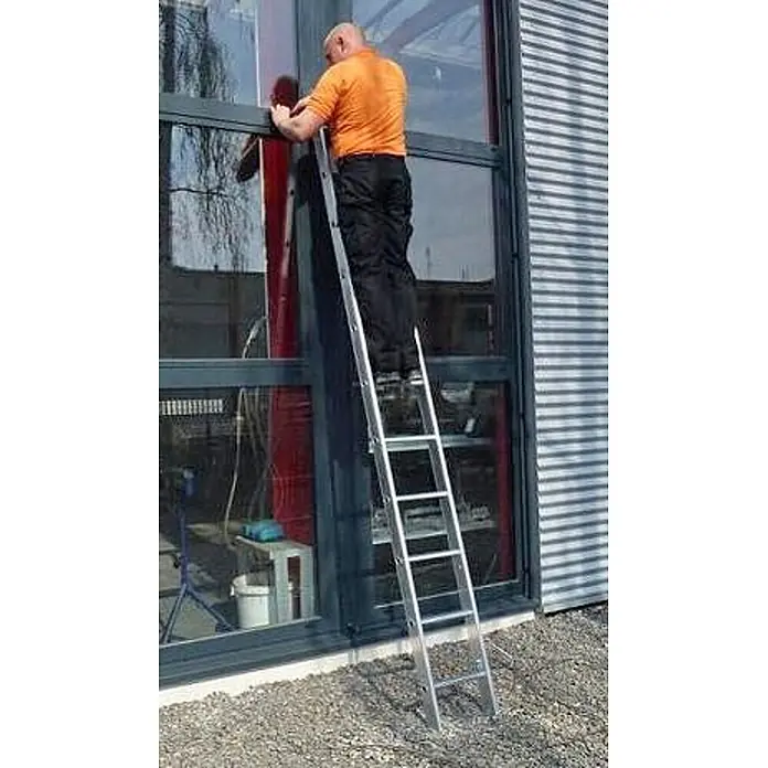 Euroline Mehrzweckleiter 207 Mehrzweckleiter 3x11 Sprossen - Anzahl Tritte: 11 Stk., Arbeitshöhe: 8.950 m, Aluminium - Mann auf einer silbernen Aluminiumleiter, arbeitet an einem Gebäudefenster.