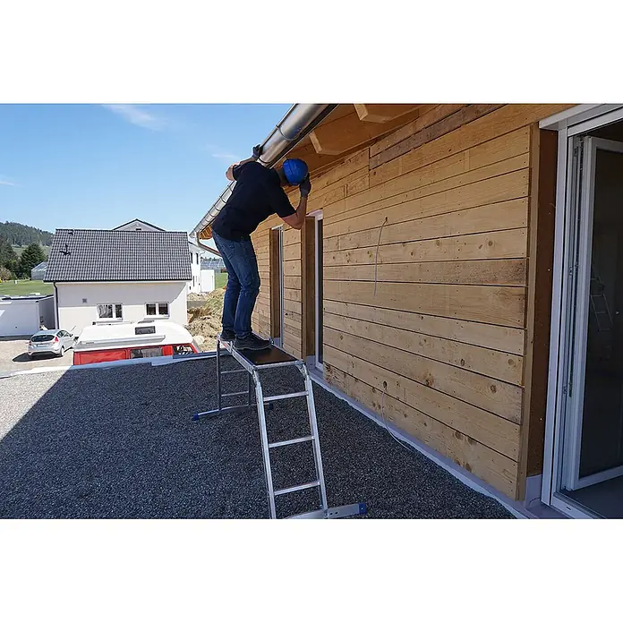 Mauderer Mehrzweckleiter Bavaria Sechsgelenkleiter als Behelfsgerüst mit Rastgelenk und gebogener T - Anzahl Tritte: 3 Stk., Arbeitshöhe: 4.400 m, Belastbarkeit: 150 kg - Klappbares Arbeitsgerüst in Silber mit dunkler Plattform, ein Mann arbeitet daran an einer Dachrinne.