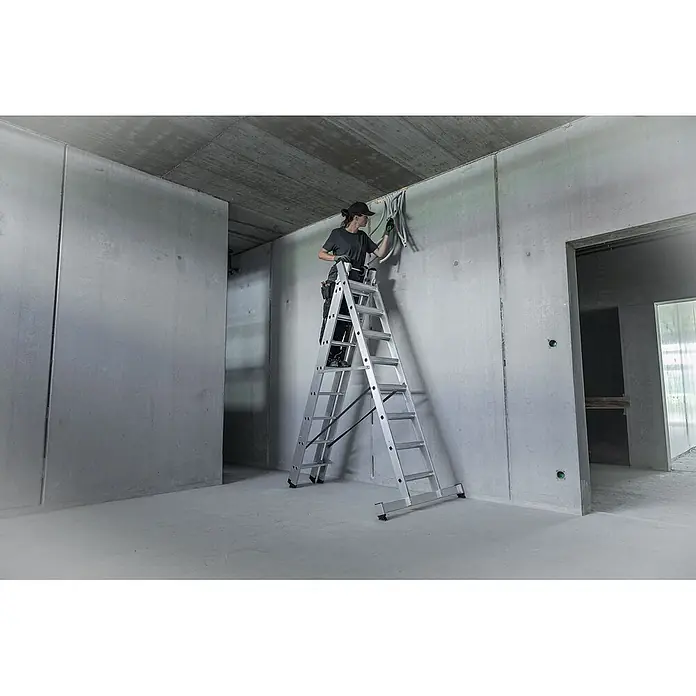 Munk Mehrzweckleiter Stufen- Mehrzweckleiter mit Wandlaufrollen, clipstep R13 und Nivello® Trav - Anzahl Tritte: 8 Stk., Arbeitshöhe: 6.900 m, Aluminium - Silberne Aluminiumleiter, von einer Frau zum Verlegen von Elektroleitungen an einer Betonwand genutzt.